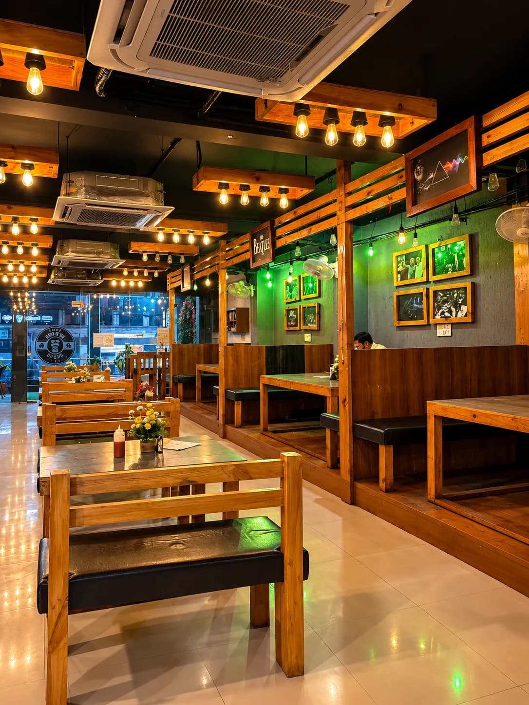 Wooden booths under Edison bulbs, rock photos on a green wall
